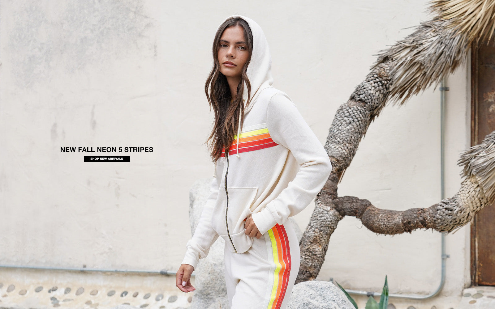 Person wearing a white hoodie with rainbow stripes outdoors