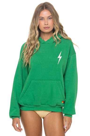 Woman wearing a green hoodie with a white lightning bolt design on a white background