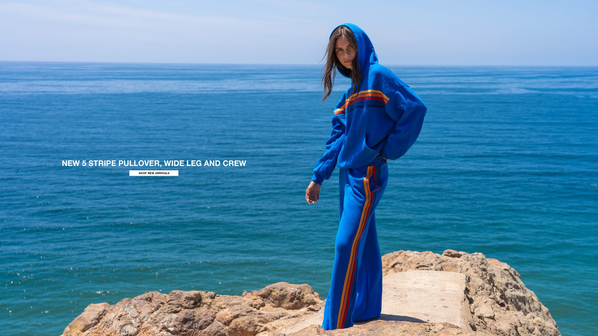 Person wearing a blue outfit with stripes by the ocean