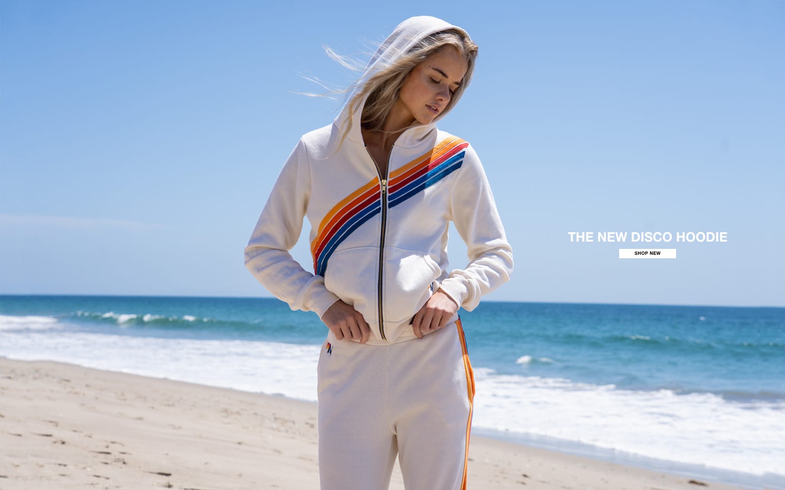 Woman wearing a white hoodie with colorful stripes on a beach