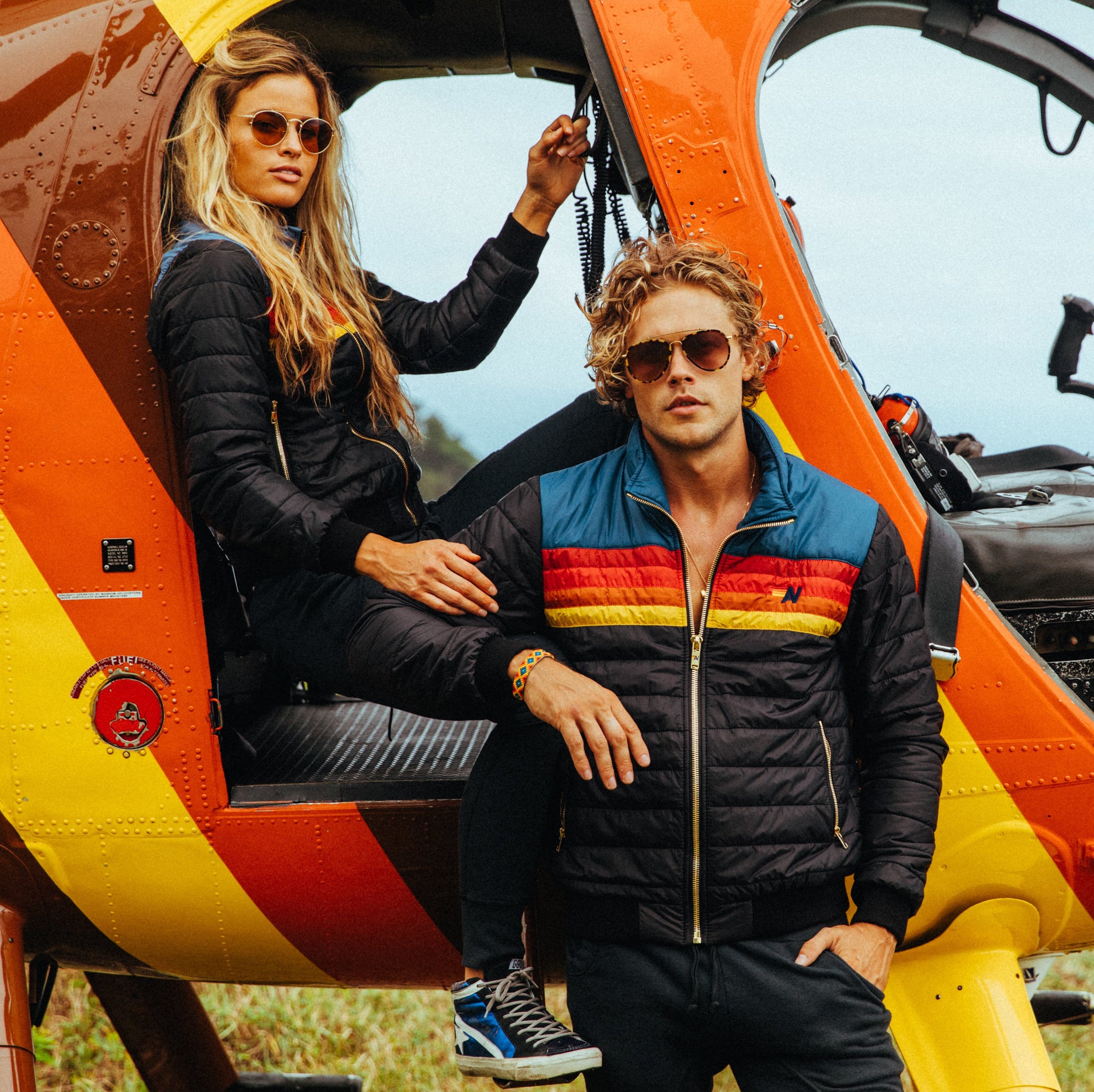 Models posing in outerwear in-front of helicopter