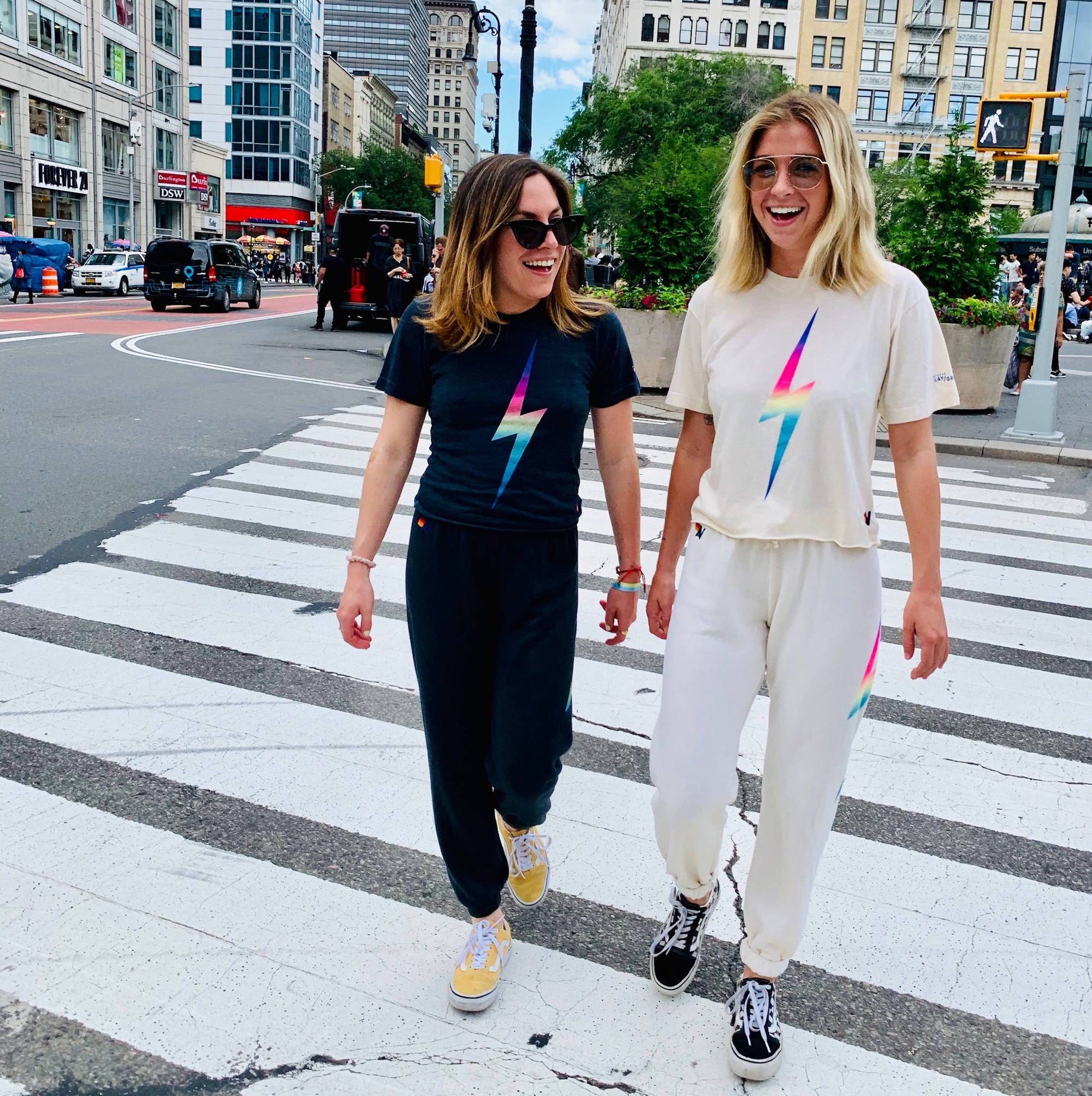 Two women walking across the street in NYC wearing Aviator Nation