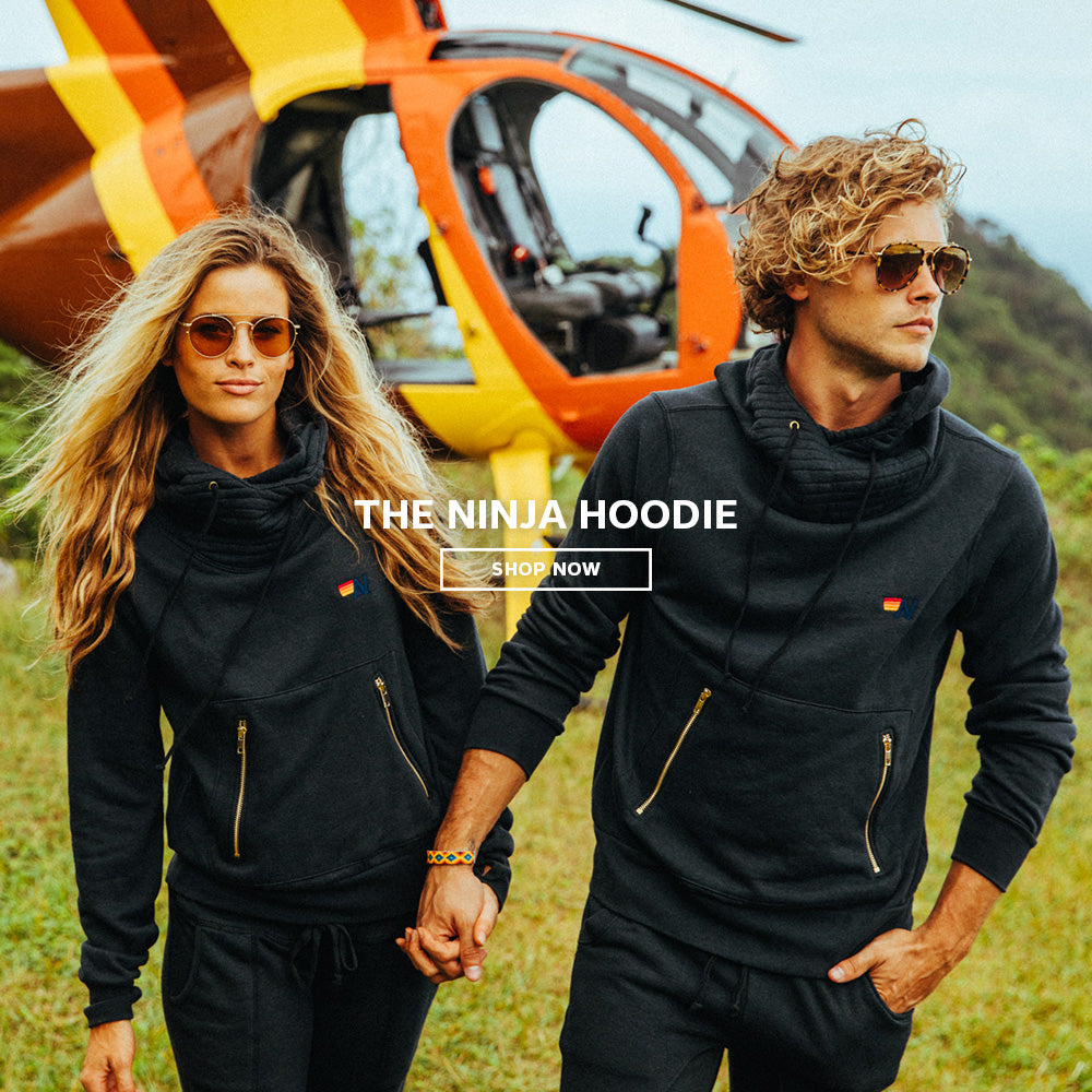 Models in black hoodies posing in front of helicopter